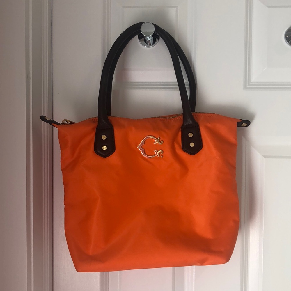 Orange tote bag with gold accents and brown leather straps